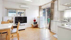 Una cocina moderna con comedor, televisor y un refrigerador pequeño.