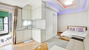 Una habitación compacta y moderna, con kitchenette, una cama con cabecera y vistas al exterior.