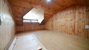 Une pièce aux murs en bois et au plafond en pente, dotée d’un puits de lumière et d’une prise électrique visible.