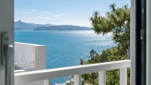 Un balcón con vistas a un mar tranquilo y montañas lejanas.