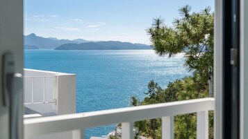 Un balcón con vistas a un mar tranquilo y montañas lejanas.