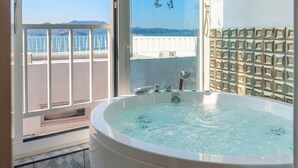 Un baño con una bañera grande, vistas al mar y un papel tapiz estampado.