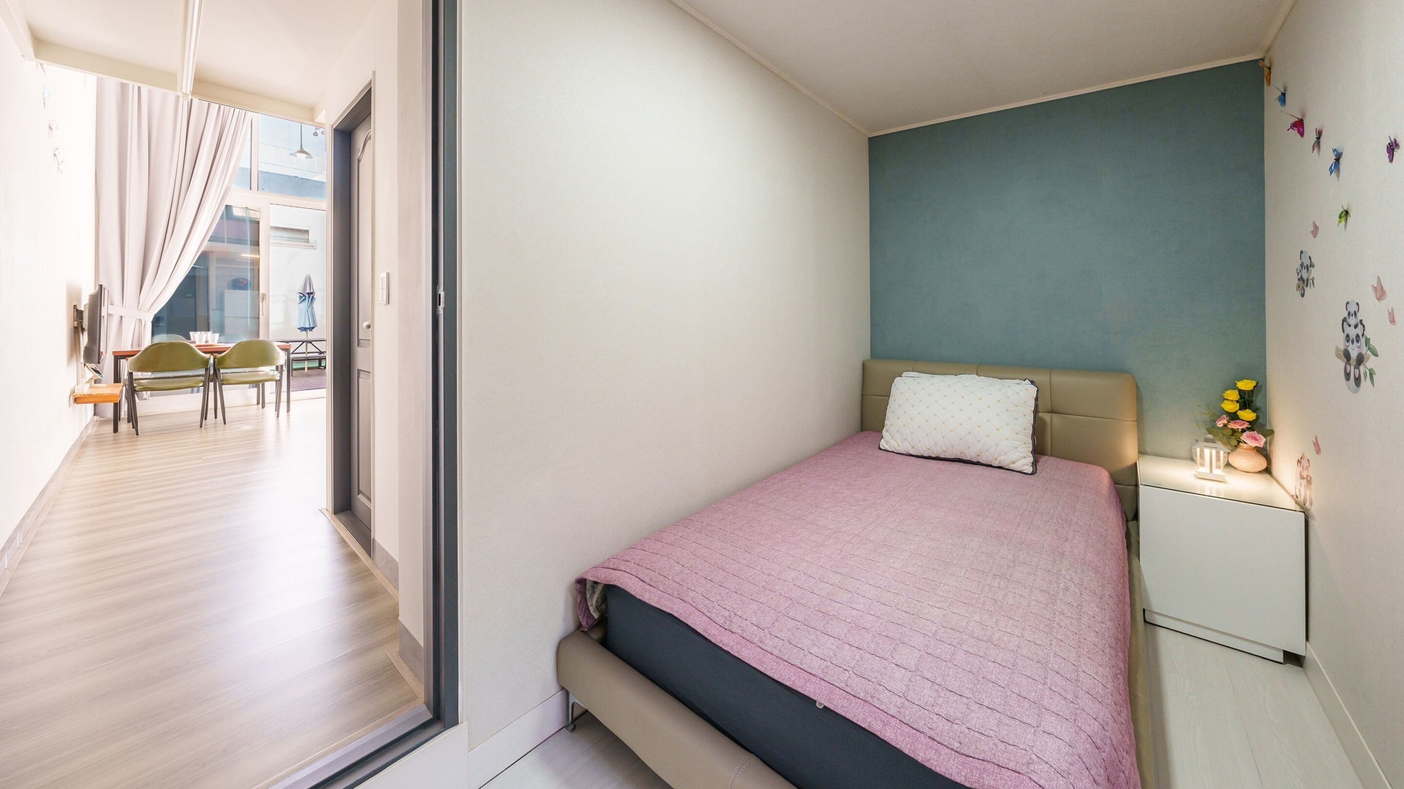 Un dormitorio con una cama, una mesita de noche y una pared decorada con pegatinas.