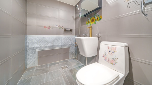 Un baño con inodoro blanco, lavamanos y ducha.