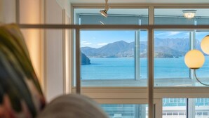 Una habitación con un gran ventanal con vistas a un cuerpo de agua y montañas.