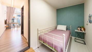 A bedroom with a single bed, a small table, and a window.
