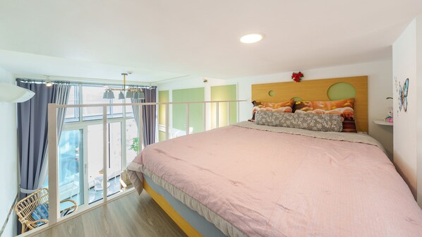 A bedroom with a large bed, a window with curtains, a rattan chair, and a small table. - Yeosu Yegreena Spa Pension (Yeosu)