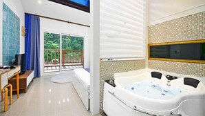 A modern bathroom with a large bathtub, a shower area, and a balcony with a view of greenery. - Gyeongju Green Valley Spa Pension (Gyeongju)
