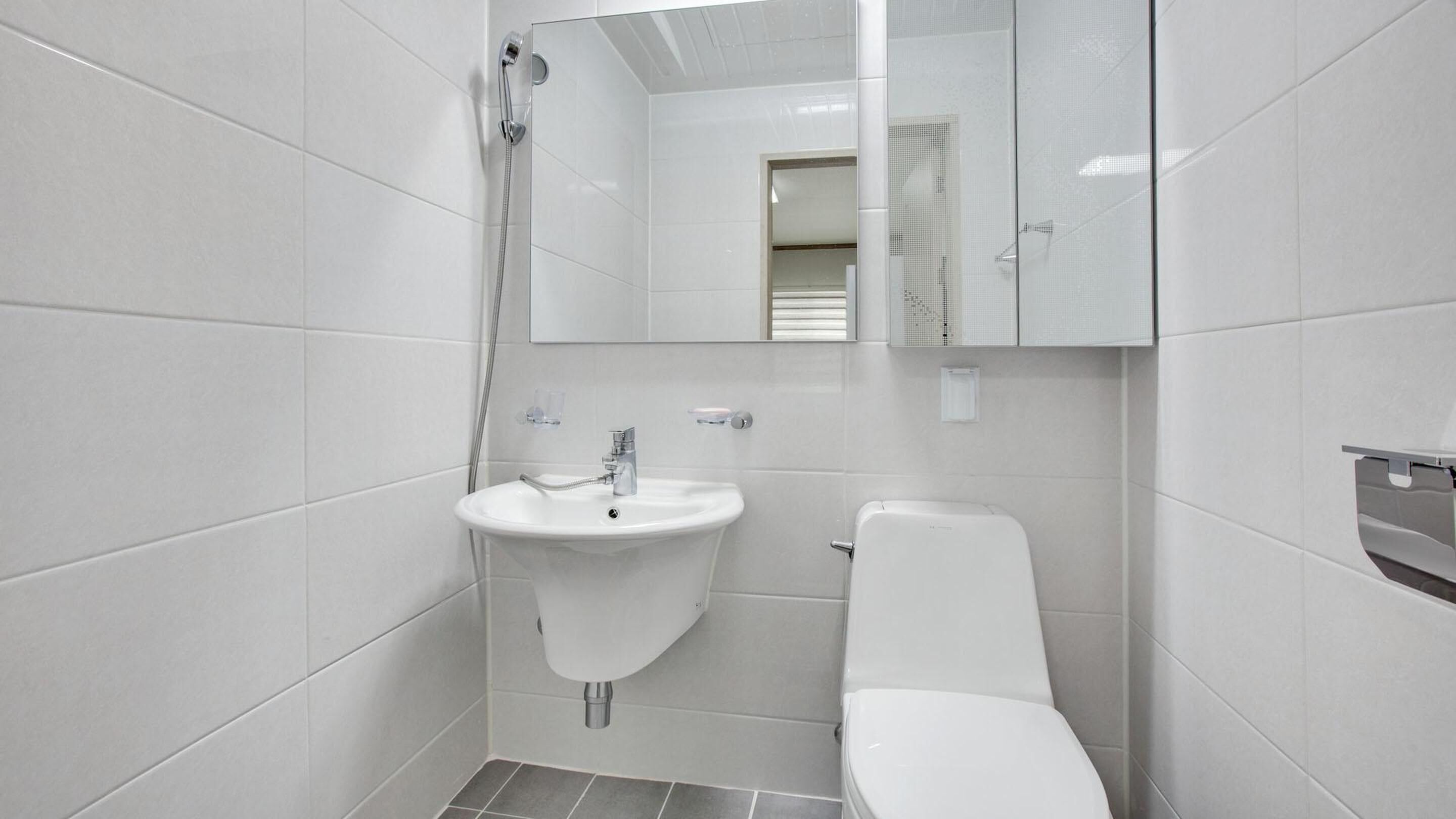 Une salle de bain moderne avec un lavabo, des toilettes et une douche, le tout de couleur blanche.