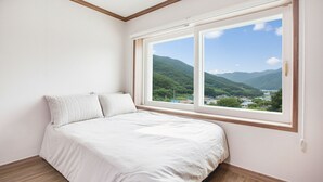 Un dormitorio con un ventanal grande, una cama y vistas a las montañas.
