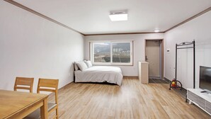 Un dormitorio con cama, ventana, puerta, televisor y escritorio.