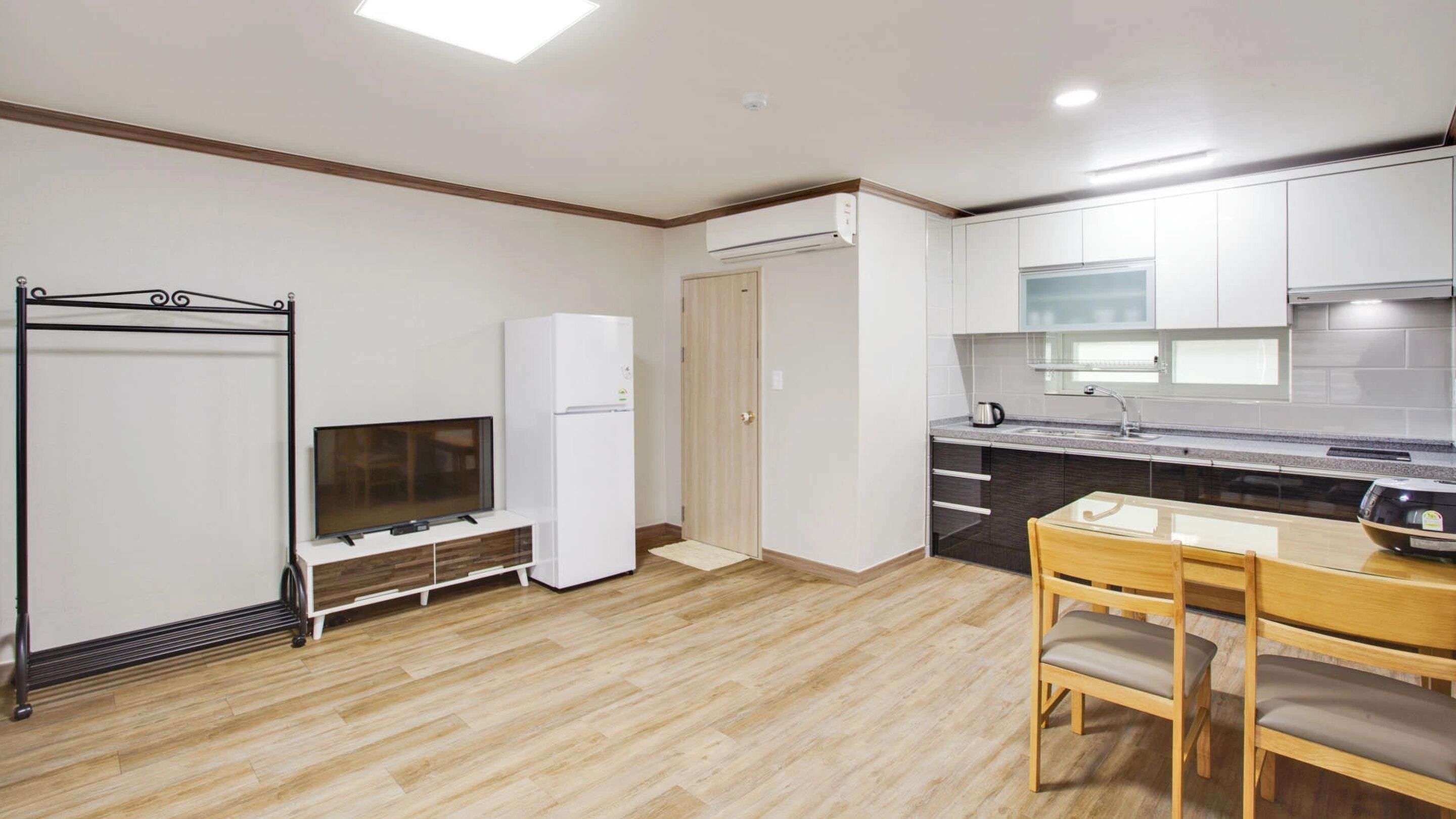Cocina compacta con televisión, refrigerador y comedor.