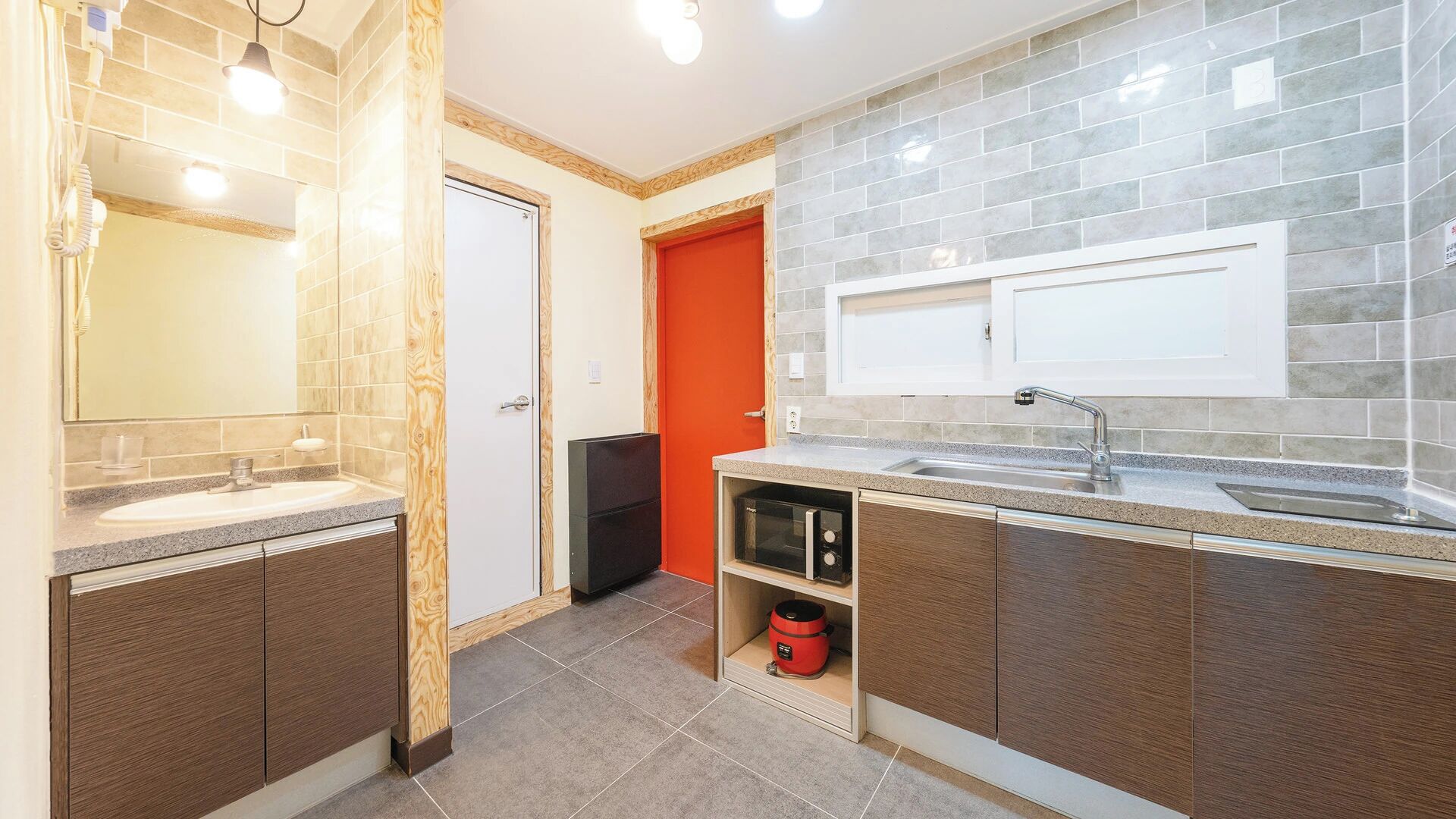 A modern bathroom with a vanity, sink, and a red door.