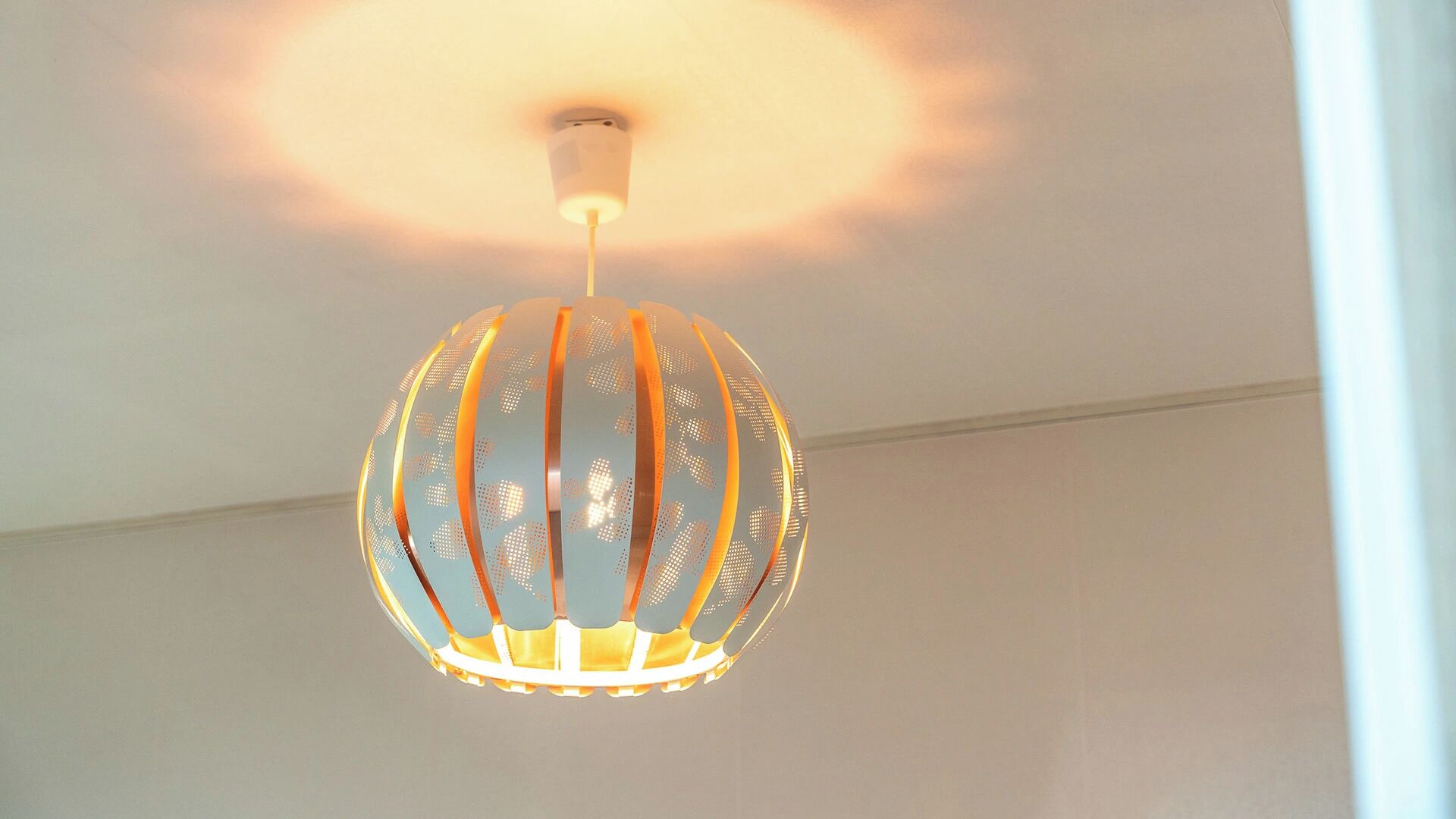 A spherical pendant light fixture with a metallic finish and a warm glow.