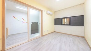 Una habitación con puerta corrediza de vidrio, aire acondicionado instalado en la pared y una ventana con persiana oscura.