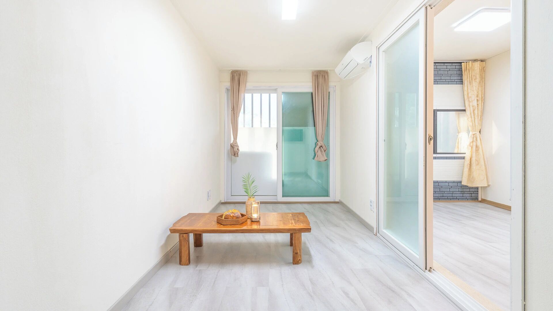 A hallway with a wooden table, a glass door, and a sliding glass door.
