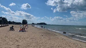 En strand där folk solar och promenerar längs strandkanten.