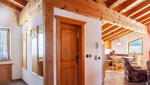 A wooden door, a mirror, a dining area with chairs, and a kitchen in the background. - Apartment "Ahornblick" with Mountain View, Wi-Fi & Balcony (Gattererberg)