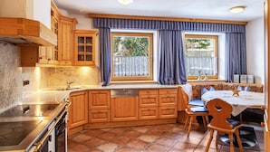 A kitchen with wooden cabinets, a built-in dishwasher, a stove, and a dining area with a table and chairs.