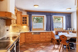 Een keuken met houten kastjes, een ingebouwde vaatwasser, een fornuis en een eethoek met een tafel en stoelen.