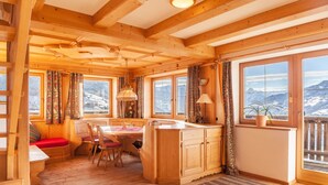 A wooden cabin interior with a dining area, a kitchen, and large windows with mountain views. - Apartment "Zillertal 3000" with Mountain View, Wi-Fi & Terrace (Gattererberbg)