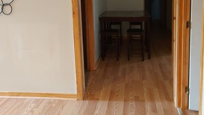 Un pasillo con suelo de madera, una mesa de comedor con sillas y una puerta a la derecha.