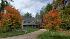 A two-story house with a porch, surrounded by trees with autumn foliage. - If you want privacy, look no further! (Arundel)