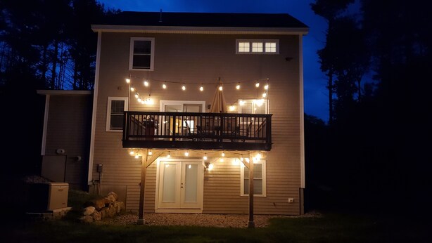 A two-story house with a balcony, string lights, and a small porch area. - If you want privacy, look no further! (Arundel)