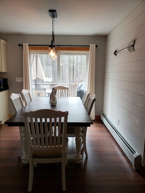 Enjoy meals in this dining area with a long table and six chairs, a decorative vase, and a pendant light.