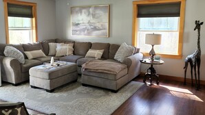 A living room with a sectional sofa, a patterned armchair, a giraffe statue, and a painting on the wall. - If you want privacy, look no further! (Arundel)
