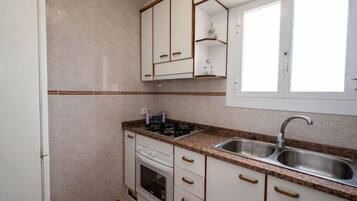 Een koelkast, een magnetron, een oven, kookgerei, borden en bestek