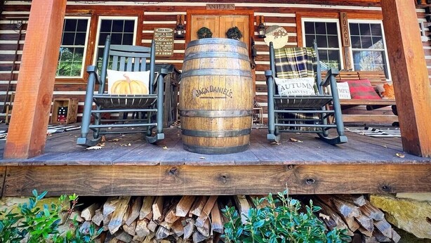 A wooden porch with two rocking chairs, a large barrel, and a sign reading "Jack Daniel's". - Natchez Hideaway ~ Rustic Cabin on 50 acres outside Nashville near Leipers Fork (Franklin)