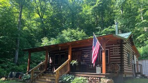 A rustic cabin with a porch, steps, and an American flag. - Natchez Hideaway ~ Rustic Cabin on 50 acres outside Nashville near Leipers Fork (Franklin)