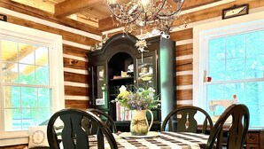 A dining room with a checkered tablecloth, wooden chairs, a chandelier, and a view of the outdoors through large windows. - Natchez Hideaway ~ Rustic Cabin on 50 acres outside Nashville near Leipers Fork (Franklin)