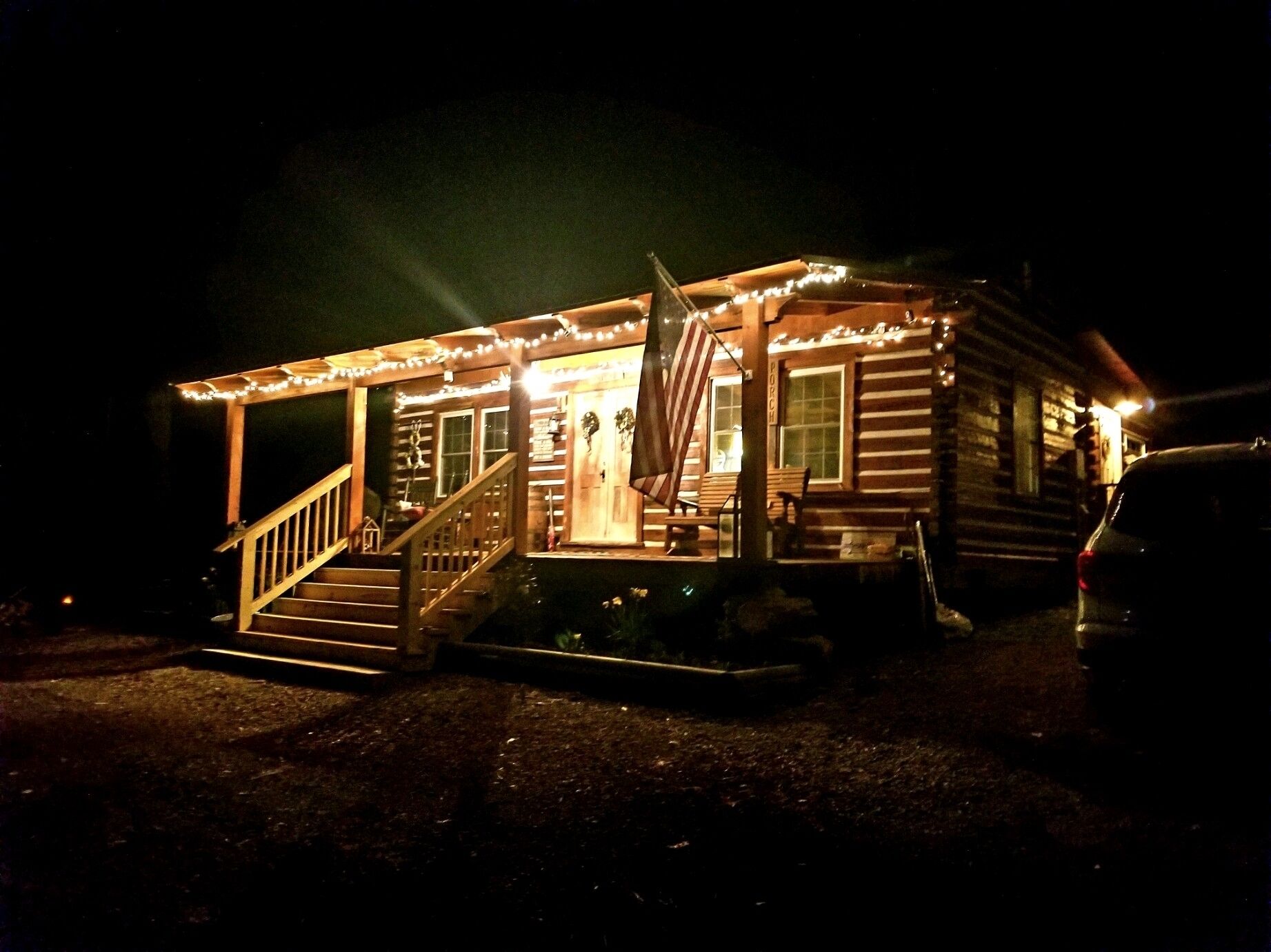 Uma cabana de madeira com varanda, escadas de madeira e uma bandeira.