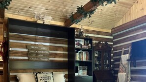 A cozy room with a bed, a bookshelf, and a wooden wall with a sign. - Natchez Hideaway ~ Rustic Cabin on 50 acres outside Nashville near Leipers Fork (Franklin)