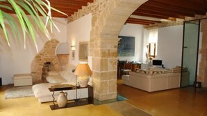 A spacious living area with a stone archway, a sofa, a coffee table, and a lamp. - Casa Muralla, Charming Old Town House with Private Pool Alcudia (Alcudia)