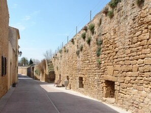 Una calle estrecha con muros de piedra y un banco.