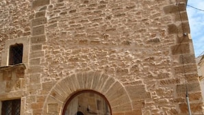 A stone building with a large arched doorway and a window with a lattice design. - Casa Muralla, Charming Old Town House with Private Pool Alcudia (Alcudia)