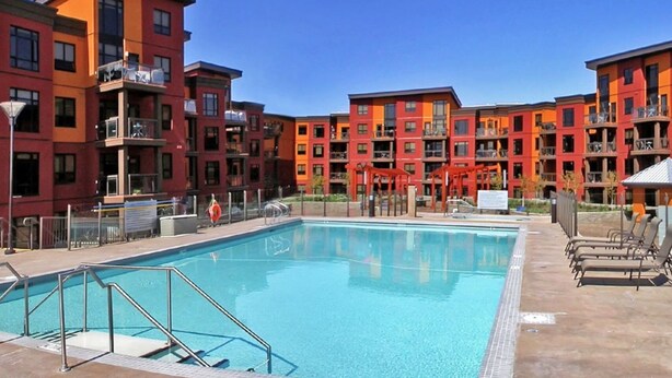 A swimming pool surrounded by multi-story buildings with balconies. - Mountainview getaway at Playa Del Sol (Kelowna)