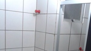 A bathroom with white tiled walls and a white countertop. There are two pink soap dishes on the counter.