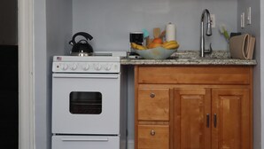 A kitchen with a white stove, wooden cabinets, a granite countertop, and a fruit bowl.