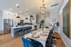 Una cocina moderna con armarios blancos, electrodomésticos de acero inoxidable y una isla central con taburetes de bar.