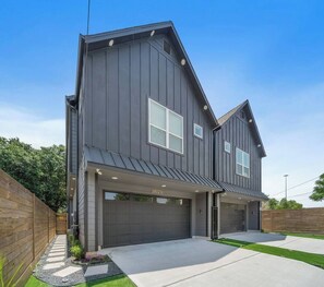Une maison à deux étages avec un garage, une allée couverte et une pelouse bien entretenue.