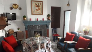 Een woonkamer met een open haard, een vloer met patroon en rode en blauwe meubels.