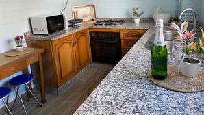 Een keuken met houten kastjes, een magnetron, een broodrooster, een spoelbak en een fles champagne.