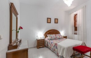 Un dormitorio con una cama, mesitas de noche, un espejo y un banco rojo.