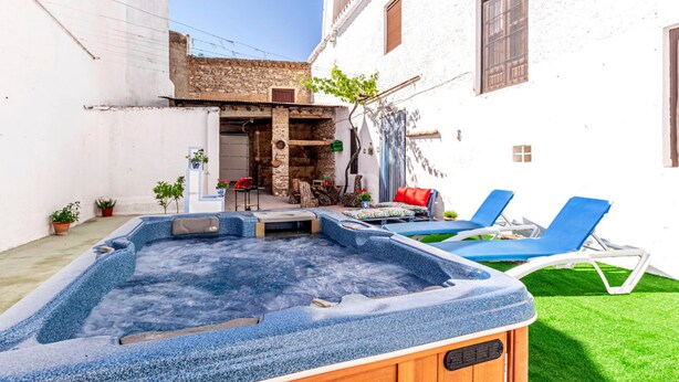 Een hottub in een binnenplaats met een klein zitgedeelte en twee loungestoelen.