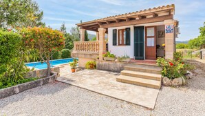 Una casa con piscina, escalones que conducen a la entrada y un jardín.