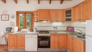 Una cocina con armarios de madera, lavavajillas, estufa y pileta.